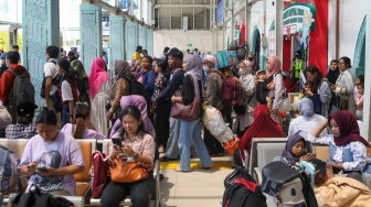 Penumpang menunggu kedatangan kereta api di Stasiun Pasar Senen, Jakarta Pusat, Senin (22/12/2025). [Suara.com/Alfian Winanto]