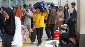 Penumpang menunggu kedatangan kereta api di Stasiun Pasar Senen, Jakarta Pusat, Senin (22/12/2025). [Suara.com/Alfian Winanto]