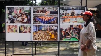 Wisatawan melihat karya foto pada pameran Haluan Merah Putih di Taman Margasatwa Ragunan (TMR) di Jakarta, Kamis (25/12/2025). [Suara.com/Alfian Winanto]

