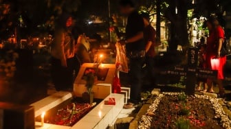 Warga keturunan Portugis saat ziarah makam anggota keluarga mereka pada malam Natal di kompleks Gereja Protestan Indonesia Barat (GPIB) Tugu, Semper Barat, Cilincing, Jakarta, Rabu (24/12/2025).  [Suara.com/Alfian Winanto]