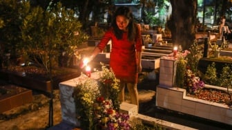 Warga keturunan Portugis menyalakan lilin saat ziarah makam anggota keluarga mereka pada malam Natal di kompleks Gereja Protestan Indonesia Barat (GPIB) Tugu, Semper Barat, Cilincing, Jakarta, Rabu (24/12/2025).  [Suara.com/Alfian Winanto]