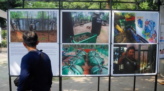 Wisatawan melihat karya foto pada pameran Haluan Merah Putih di Taman Margasatwa Ragunan (TMR) di Jakarta, Kamis (25/12/2025). [Suara.com/Alfian Winanto]
