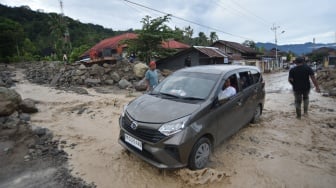 Mobil melewati aliran sungai yang menggenangi jalan pascabanjir bandang susulan di Nagari Maninjau, Agam, Sumatera Barat, Jumat (26/12/2025). [ANTARA FOTO/Iggoy el Fitra/wpa]