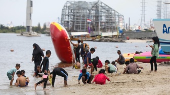 Pengunjung berwisata di Pantai Lagoon, Taman Impian Jaya Ancol, Jakarta, Jumat (26/12/2025). [Suara.com/Alfian Winanto]