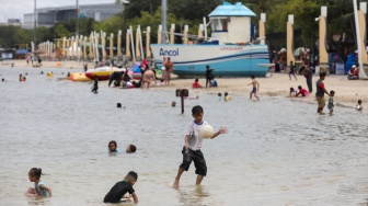 Pengunjung berwisata di Pantai Lagoon, Taman Impian Jaya Ancol, Jakarta, Jumat (26/12/2025). [Suara.com/Alfian Winanto]