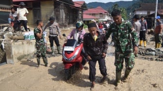 Prajurit TNI membantu warga menyeberang pascabanjir bandang susulan di Nagari Maninjau, Agam, Sumatera Barat, Jumat (26/12/2025). [ANTARA FOTO/Iggoy el Fitra/wpa]