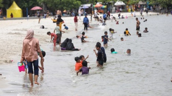 Pengunjung berwisata di Pantai Lagoon, Taman Impian Jaya Ancol, Jakarta, Jumat (26/12/2025). [Suara.com/Alfian Winanto]