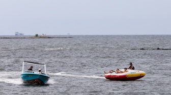 Pengunjung berwisata di Pantai Lagoon, Taman Impian Jaya Ancol, Jakarta, Jumat (26/12/2025). [Suara.com/Alfian Winanto]