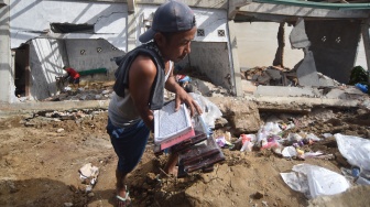 Warga menyelamatkan Al Quran dari bangunan Taman Pendidikan Al-Quran di kawasan Masjid Jamaatul Yaqin Banda Cino, Talao Mundam, Nagari Katapiang, Padang Pariaman, Sumatera Barat, Minggu (4/1/2026). [ANTARA FOTO/Iggoy el Fitra/nym]