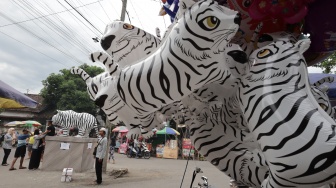 Pengunjung memotret patung Macan Putih dengan latar depan balon menyerupai macan putih di Desa Balongjeruk, Kabupaten Kediri, Jawa Timur, Senin (5/1/2026). [ANTARA FOTO/Prasetia Fauzani/nz]