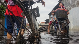 Warga mendorong sepedanya melewati jalan perkampungan yang tergenang banjir di Pabean, Kota Pekalongan, Jawa Tengah, Rabu (7/1/2026). [ANTARA FOTO/Harviyan Perdana Putra/foc]
