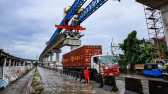 Kendaraan truk melewati banjir yang menggenang di Jalan RE Martadinata, Tanjung Priok, Jakarta, Senin (12/1/2026). [Suara.com/Alfian Winanto]
