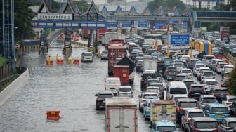 Petugas memasang pembatas jalan di gerbang tol yang terendam banjir di Jalan Tol Sedyatmo, Cengkareng, Jakarta, Senin (12/1/2026). [ANTARA FOTO/Putra M. Akbar/nz]