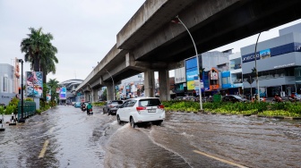 Pengendara melewati banjir yang menggenang di Jalan Boulevard Raya, Kelapa Gading, Jakarta, Senin (12/1/2026). [Suara.com/Alfian Winanto]