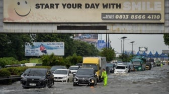 Polisi mengatur lalu lintas kendaraan saat banjir di Jalan Tol Sedyatmo, Kota Tangerang, Banten, Senin (12/1/2026). [ANTARA FOTO/Putra M. Akbar/nz]