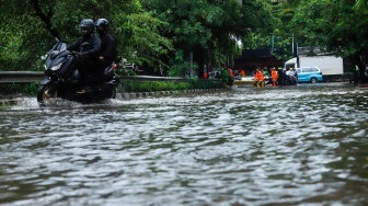 Pengendara motor menorobos banjir yang menggenang di Jalan Danau Sunter Raya, Jakarta, Senin (12/1/2026). [Suara.com/Alfian Winanto]