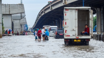 Kendaraan truk melewati banjir yang menggenang di Jalan RE Martadinata, Tanjung Priok, Jakarta, Senin (12/1/2026). [Suara.com/Alfian Winanto]