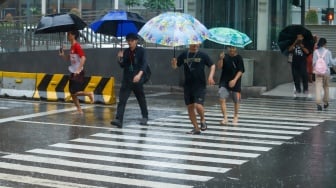 Sejumlah warga beraktivitas saat turun hujan di kawasan Bundaran HI, Jakarta, Selasa (13/1/2026). [Suara.com/Alfian Winanto]
