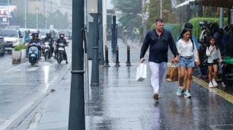 Sejumlah warga beraktivitas saat turun hujan di kawasan Bundaran HI, Jakarta, Selasa (13/1/2026). [Suara.com/Alfian Winanto]
