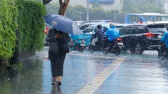 Sejumlah warga beraktivitas saat turun hujan di kawasan Bundaran HI, Jakarta, Selasa (13/1/2026). [Suara.com/Alfian Winanto]
