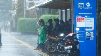 Sejumlah warga beraktivitas saat turun hujan di kawasan Bundaran HI, Jakarta, Selasa (13/1/2026). [Suara.com/Alfian Winanto]
