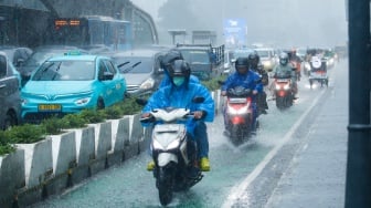 Sejumlah warga beraktivitas saat turun hujan di kawasan Bundaran HI, Jakarta, Selasa (13/1/2026). [Suara.com/Alfian Winanto]
