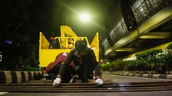 Petugas merapikan besi tiang monorel usai dibongkar di Jalan H. R. Rasuna Said, Jakarta, Rabu (14/1/2026). [Suara.com/Alfian Winanto]