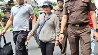 Petugas menggiring buronan terpidana kasus korupsi pemberian kredit fiktif Mila Indriani Notowibowo (tengah) di Kantor Kejaksaan Tinggi Bali, Denpasar, Bali, Rabu (14/1/2026). [ANTARA FOTO/Fikri Yusuf/foc]