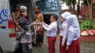 Relawan Satuan Pelayanan Pemenuhan Gizi (SPPG) Danupayan berpakaian seni Warokan saat membagikan paket makan bergizi gratis (MBG) kepada pelajar SD Negeri Pandemulyo di Bulu, Temanggung, Jawa Tengah, Senin (19/1/2026). [ANTARA FOTO/Anis Efizudin/wsj]