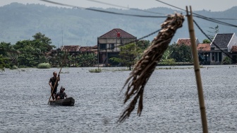 Warga menggunakan rakit untuk menyeberangi akses jalan yang terendam banjir di Desa Mejobo, Kudus, Jawa Tengah, Senin (19/1/2026). [ANTARA FOTO/Aprillio Akbar/rwa]