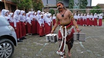 Relawan Satuan Pelayanan Pemenuhan Gizi (SPPG) Danupayan berpakaian seni Warokan saat mendistribusikan makan bergizi gratis (MBG) ke SD Negeri Pandemulyo di Bulu, Temanggung, Jawa Tengah, Senin (19/1/2026). [ANTARA FOTO/Anis Efizudin/wsj]
