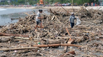 Warga bejalan di atas tumpukan sampah kiriman di Pantai Kuta, Badung, Bali, Senin (19/1/2026). [ANTARA FOTO/Nyoman Hendra Wibowo/tom]