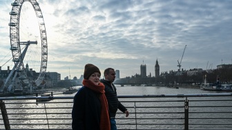 Warga melintasi jembatan di atas Sungai Thames dengan latar belakang London Eye di London, Inggris, Minggu (18/1/2026). [ANTARA FOTO/Galih Pradipta/wsj]
