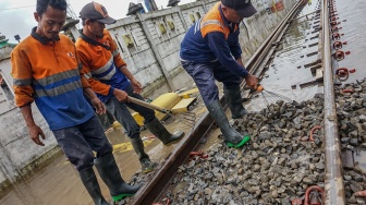 Sejumlah pekerja meratakan batu kricak (ballast) pada jalur rel kereta api yang terdampak banjir di sekitar Stasiun Pekalongan, Kota Pekalongan, Jawa Tengah, Rabu (21/1/2026). [ANTARA FOTO/Harviyan Perdana Putra/wsj]
