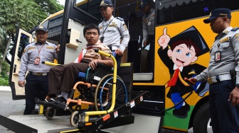 Petugas Dishub membantu siswa penyandang disabilitas menaiki bus sekolah ramah disabilitas saat peluncuran armada tersebut di Pendopo Balai Kota, Jakarta, Rabu (21/1/2026). [ANTARA FOTO/Indrianto Eko Suwarso/bar]