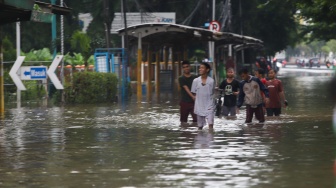 Warga beraktivitas di tengah genangan banjir yang merendam di sekitar Cempaka Putih, Jakarta, Kamis (22/1/2026). [Suara.com/Alfian Winanto]
