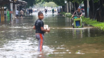 Warga beraktivitas di tengah genangan banjir yang merendam di sekitar Cempaka Putih, Jakarta, Kamis (22/1/2026). [Suara.com/Alfian Winanto]
