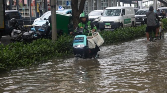 Warga beraktivitas di tengah genangan banjir yang merendam di sekitar Cempaka Putih, Jakarta, Kamis (22/1/2026). [Suara.com/Alfian Winanto]
