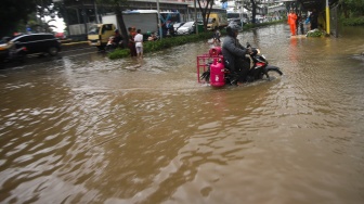 Warga beraktivitas di tengah genangan banjir yang merendam di sekitar Cempaka Putih, Jakarta, Kamis (22/1/2026). [Suara.com/Alfian Winanto]
