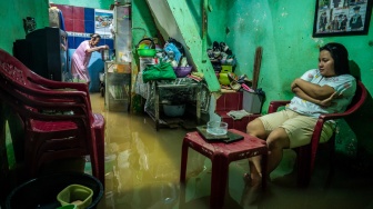 Warga berada di rumah saat banjir merendam perkampungan di Kebon Pala, Jatinegara, Jakarta, Jumat (23/1/2026). [ANTARA FOTO/Bayu Pratama S/foc]
