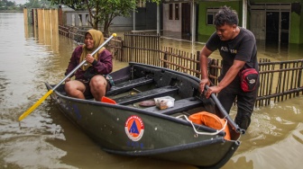 Dua warga menggunakan perahu untuk melintasi permukiman yang terendam banjir di Desa Karangligar, Telukjambe, Karawang, Jawa Barat, Kamis (22/1/2026). [ANTARA FOTO/Darryl Ramadhan/app/tom]