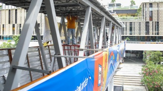 Pekerja menyelesaikan pembangunan Jembatan Penyeberangan Orang (JPO) Sarinah, Jakarta Pusat, Senin (26/1/2026). [Suara.com/Alfian Winanto]