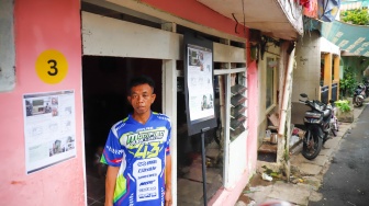 Warga berdiri di depan rumahnya yang sudah direnovasi di perkampungan padat penduduk, kawasan Menteng Tenggulun, Jakarta, Rabu (28/1/2026). [Suara.com/Alfian Winanto]