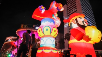 Warga melihat instalasi pencahayaan dalam Jakarta Light Festival edisi Imlek di kawasan Bundaran HI, Jakarta, Jumat (13/2/2026). [Suara.com/Alfian Winanto]
