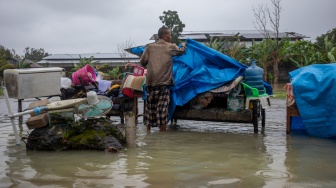 Seorang warga Mustakim (55) menutup sejumlah barang dengan terpal agar tidak kehujanan di tengah banjir yang menggenangi Desa Pilangwetan, Kecamatan Kebonagung,Kabupaten Demak, Jawa Tengah, Selasa (17/2/2026). [ANTARA FOTO/Aji Styawan/bar]
