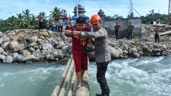 Polisi membantu penyintas bencana menyeberangi jembatan darurat di Jorong Kayu Pasak Selatan, Nagari Salareh Aia, Palembayan, Agam, Sumatera Barat, Rabu (18/2/2026). [ANTARA FOTO/Wahdi Septiawan/YU]

