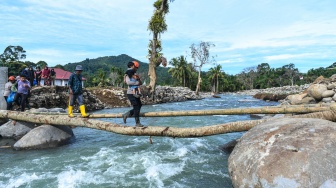 Polisi membantu penyintas bencana menyeberangi jembatan darurat di Jorong Kayu Pasak Selatan, Nagari Salareh Aia, Palembayan, Agam, Sumatera Barat, Rabu (18/2/2026). [ANTARA FOTO/Wahdi Septiawan/YU]