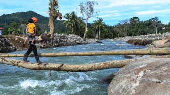 Polisi membantu penyintas bencana menyeberangi jembatan darurat di Jorong Kayu Pasak Selatan, Nagari Salareh Aia, Palembayan, Agam, Sumatera Barat, Rabu (18/2/2026). [ANTARA FOTO/Wahdi Septiawan/YU]