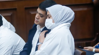 Terdakwa kasus dugaan korupsi tata kelola minyak mentah dan produk kilang Muhammad Kerry Adrianto Riza ditemani istrinya Atya Irdita Sardadi menunggu jalannya sidang di Pengadilan Tipikor, Jakarta, Kamis (19/2/2026). [Suara.com/Alfian Winanto]