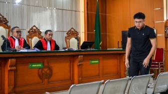 Tersangka dugaan kasus penghinaan terhadap Suku Sunda Muhammad Adimas Firdaus Putra Nasihan alias Resbob (kanan) berjalan menuju kursi saat menjalani sidang perdana di Pengadilan Negeri Bandung, Jawa Barat, Senin (23/2/2026). [ANTARA FOTO/Raisan Al Farisi/YU]